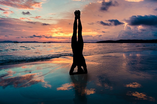 瑜伽的立场在手中的剪影, 落日下的海滩, 由海禅位置